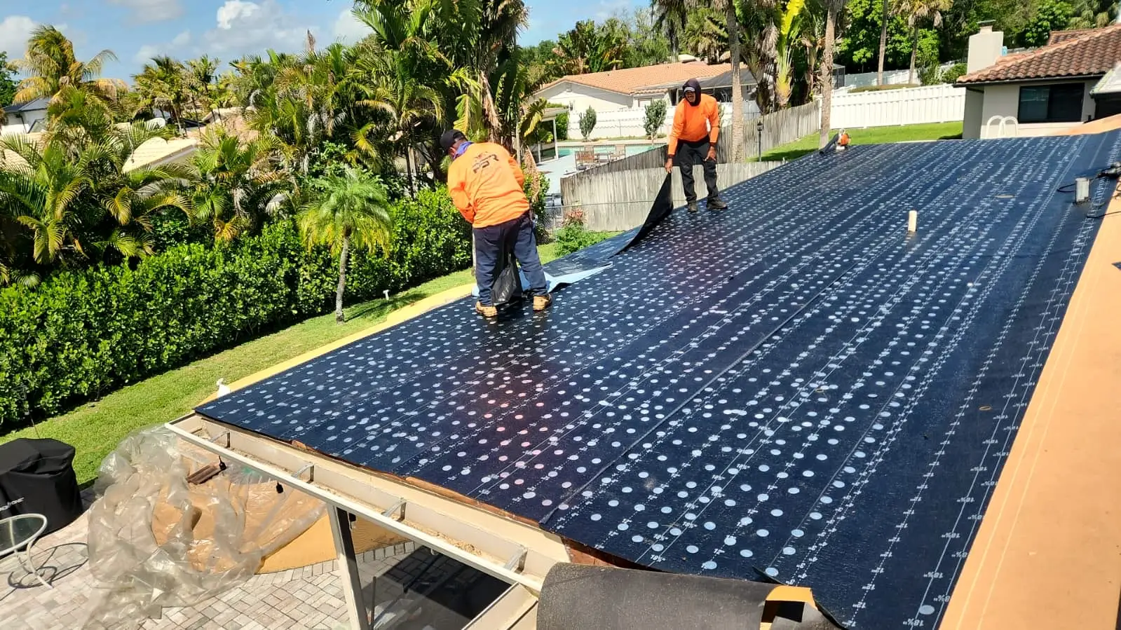 Two PSR crew members rolling out underlayment across a roof