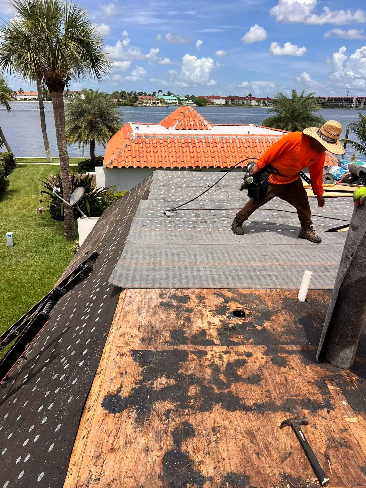 PSR crew member fastening underlayment on a roof deck beside the water