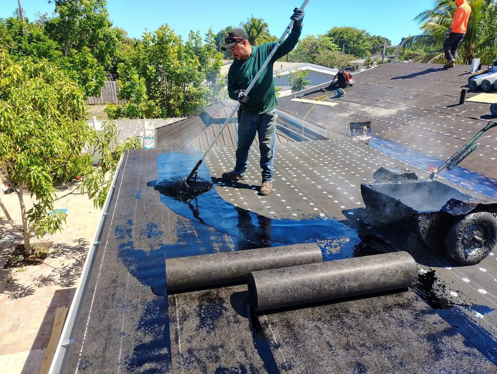 Roofer mopping hot asphalt on a flat roof