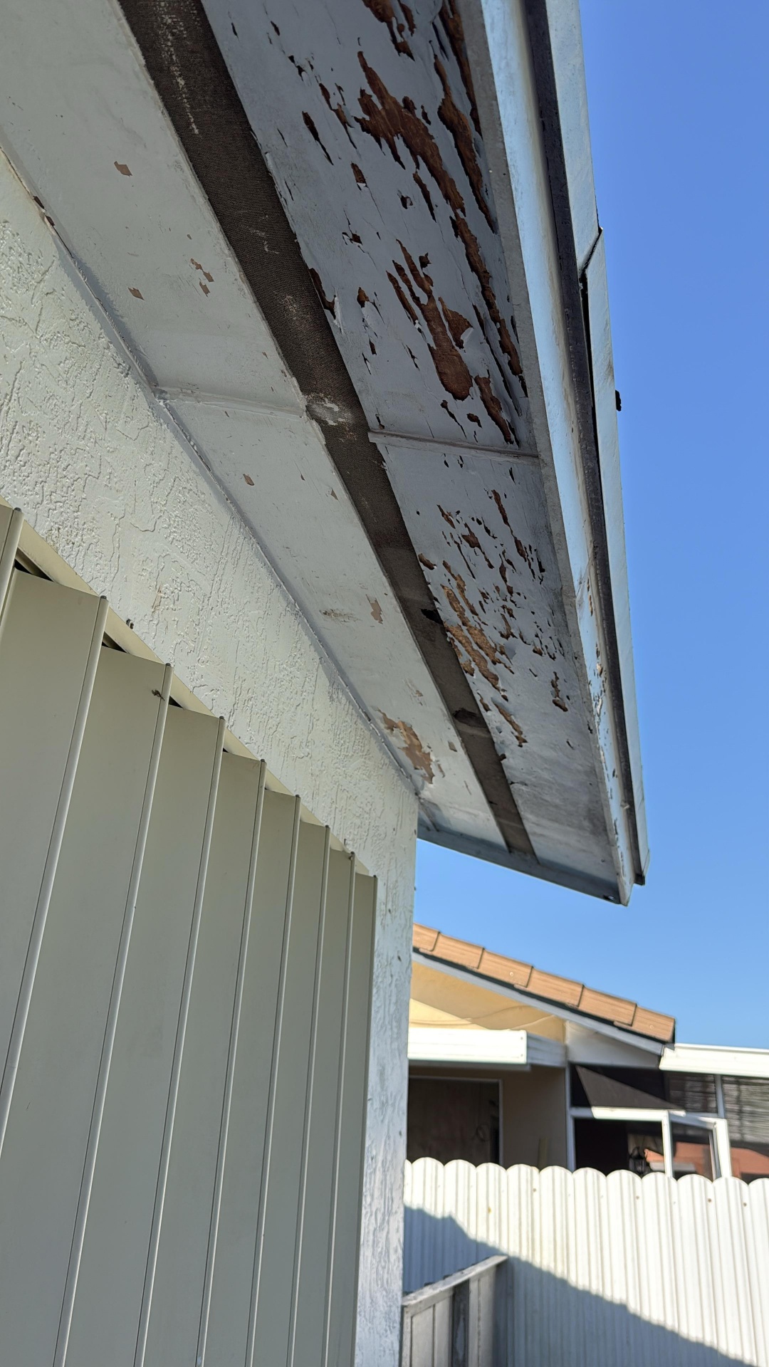 Wind-lifted roof section photographed during emergency roofing services on a Miami home